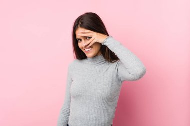 Genç ve tatlı bir kadın kameraya parmaklarıyla göz kırpıyor, utanarak yüzünü kapatıyor..