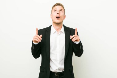 Kafkasyalı genç iş adamı ağzı açık bir şekilde üst tarafı işaret ediyor..