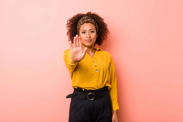 一个有着粉色背景的年轻的非洲裔美国女人站在那里 伸出的手显示出停止的迹象 阻止了你 — 图库照片