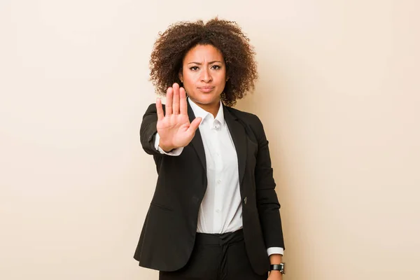 Young business african american woman standing with outstretched hand showing stop sign, preventing you.