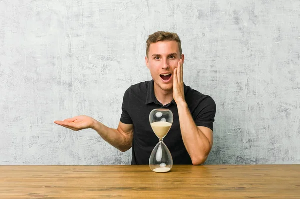 Young Man Holding Sand Timer Table Holds Copy Space Palm — Stock Photo, Image