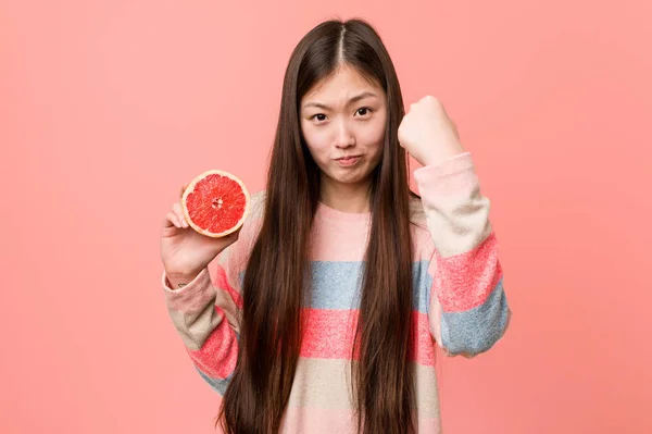Mladá Asijská Žena Grapefruitem Ukazující Pěst Kameře Agresivní Výraz Obličeje — Stock fotografie