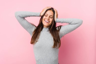 Genç ve tatlı bir kadın ellerini başının üstünde tutarak neşe içinde gülüyor. Mutluluk kavramı.