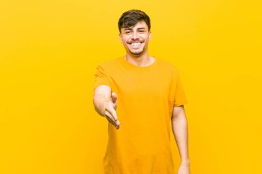 Genç Latin asıllı sıradan bir adam selamlaşmak için kameraya elini uzatıyor..