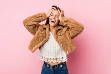 Genç ve tatlı bir kadın ellerini başının üstünde tutarak neşe içinde gülüyor. Mutluluk kavramı.