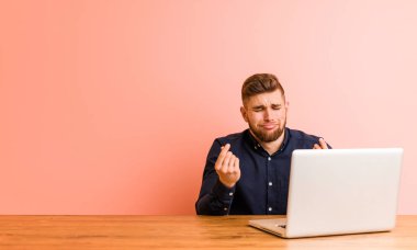 Young man working with his laptop showing that he has no money.
