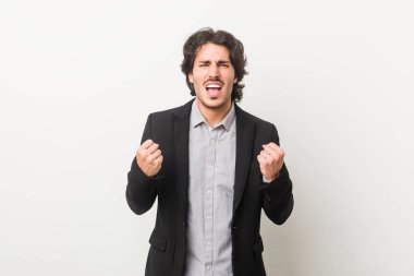 Genç bir iş adamı beyaz bir arka plana karşı gamsız ve heyecanlı tezahüratlar yapıyor. Zafer konsepti.