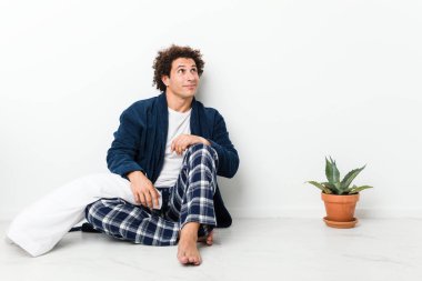 Olgun bir adam pijamasını giymiş evde oturmuş amaçlarına ve amaçlarına ulaşmayı hayal ediyor.