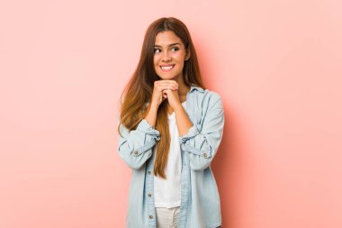 Genç sıska kadın ellerini çenesinin altında tutuyor, mutlu bir şekilde yan tarafa bakıyor..