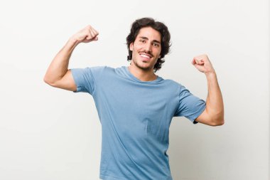 Beyaz arka planda genç ve yakışıklı bir adam. Güçlü bir jest yapıyor. Kadınsı gücün sembolü.