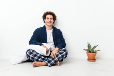 Olgun bir adam pijamasını giymiş evde oturmuş kendine güveniyor ve ellerini kalçasında tutuyor..