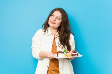 Genç, kıvrımlı bir kadın elinde tatlı bir pasta tutarak amaçlarına ve amaçlarına ulaşmayı hayal ediyor.