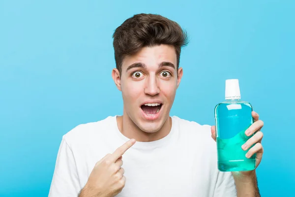 Young Caucasian Man Holding Mouthwash Surprised Pointing Himself Smiling Broadly — Stock Photo, Image