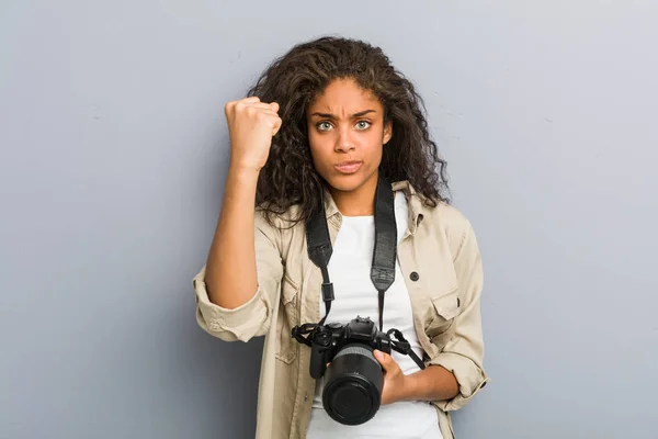 若いアフリカ系アメリカ人の写真家の女性がカメラに拳を示すカメラを持ち 積極的な表情 — ストック写真