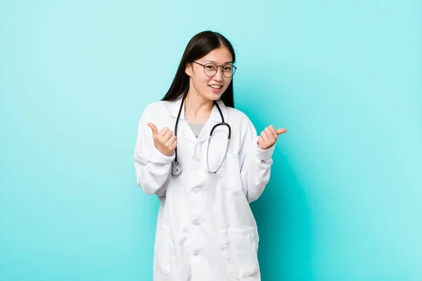 Young chinese doctor woman raising both thumbs up, smiling and confident.