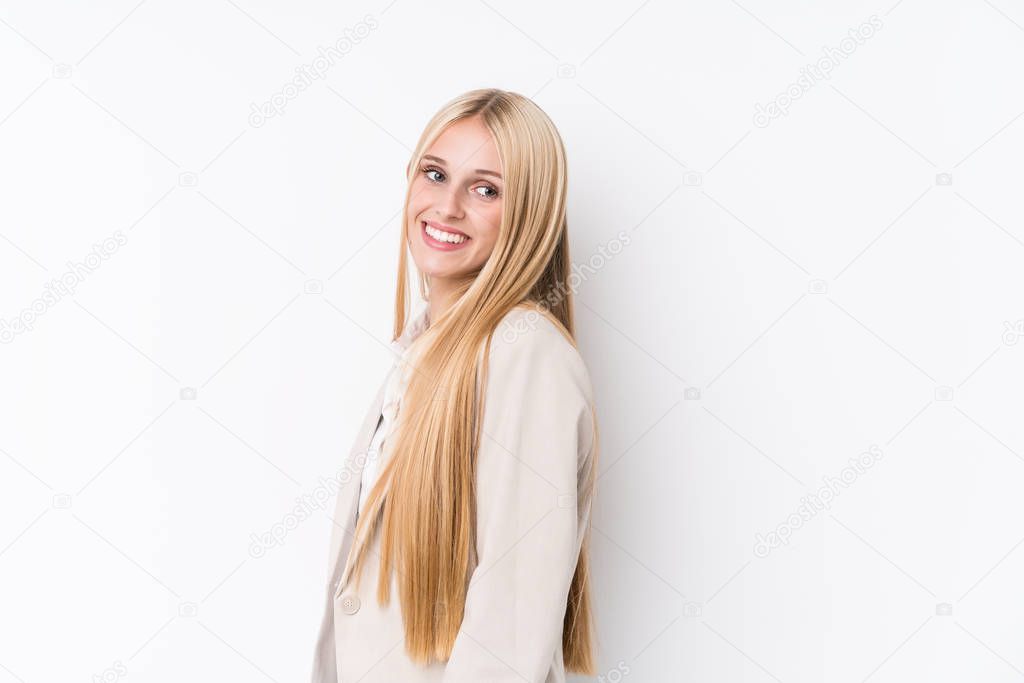 Young business blonde woman on white background looks aside smiling, cheerful and pleasant.