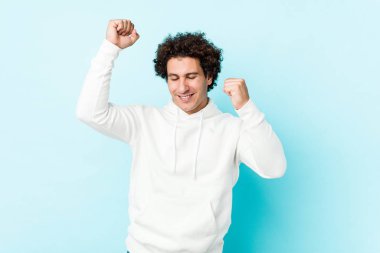 Özel bir günü kutlayan mavi arka planda genç sporcu kollarını enerji ile kaldırıyor..