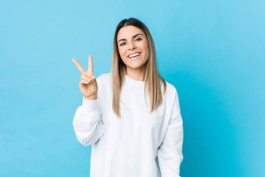 Kafkasyalı genç kadın neşeli ve kaygısız izole edilmiş parmaklarıyla barış sembolü gösteriyor..