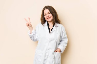 Genç doktor kadın neşeli ve kaygısız parmaklarıyla barış sembolü gösteriyor..