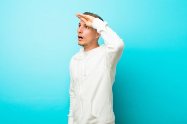 Kafkasyalı genç sporcu çok uzaklara bakıyor ve elini alnına koyuyor..