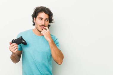 Elinde oyun kumandası olan genç adam rahatlamış fotokopi alanına bakan bir şey düşünüyor..