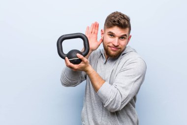 Kafkasyalı genç bir sporcu elinde bir dambılla bir dedikoduyu dinlemeye çalışıyor..