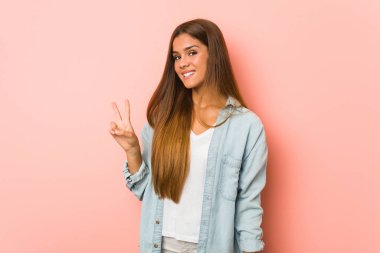 Genç, sıska, neşeli ve tasasız bir kadın parmaklarıyla barış sembolü gösteriyor..