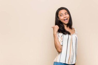 Genç, sevimli Çinli genç, sarışın kadın pembe arka planda bir ceket giyiyor, başparmak uzakta, gülüyor ve kaygısız..