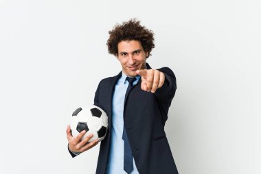 Futbol antrenörü elinde neşe dolu bir gülümsemeyle öne bakıyor..