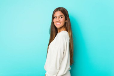 Genç sıska kadın gülümseyen, neşeli ve hoş bir şekilde yana bakıyor..