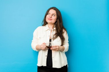 Genç kavisli kadın elinde çay fincanı tutarak amaçlarına ve amaçlarına ulaşmayı hayal ediyor.