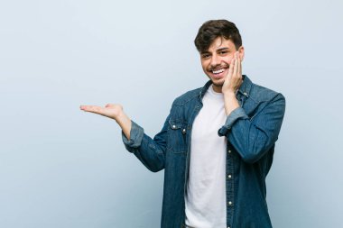 Genç, İspanyol asıllı, havalı bir adam avucunun içinde fotokopi alanı tutuyor, el üstünde tutuyor. Şaşırmış ve mutlu..