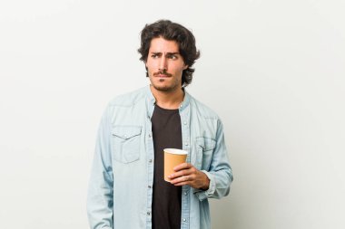 Kafası karışmış, kendinden emin olmayan genç bir adam kahve içiyor..