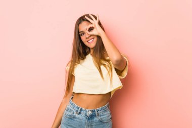 Young slim woman excited keeping ok gesture on eye.