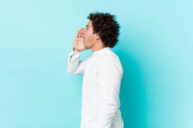 Genç, kıvırcık, olgun, zarif bir gömlek giymiş bağıran ve avuç içini açık tutan bir adam..