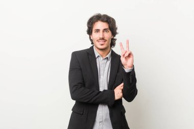 Genç bir iş adamı beyaz bir arkaplanda iki numarayı parmaklarıyla gösteriyor..