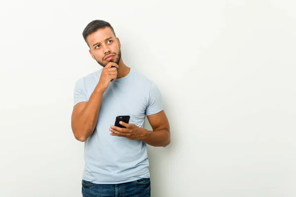 Ung Blandras Asiatisk Man Som Håller Telefon Tittar Sidled Med — Stockfoto