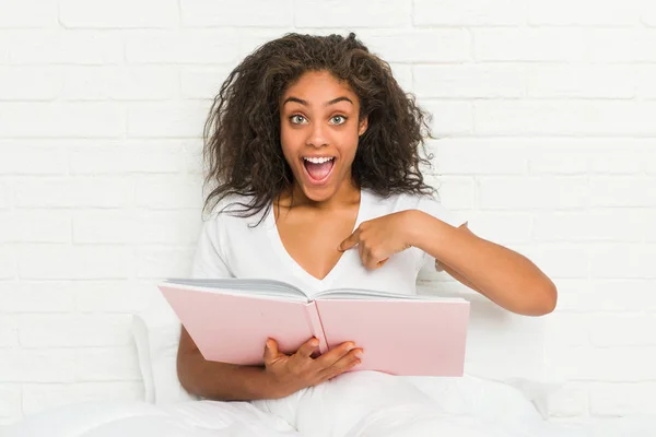 Jovem Afro Americana Sentada Cama Estudando Surpreso Apontando Para Mesmo — Fotografia de Stock