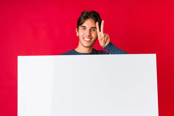 Młody Człowiek Tabliczką Pokazującą Znak Zwycięstwa Uśmiechający Się Szeroko — Zdjęcie stockowe