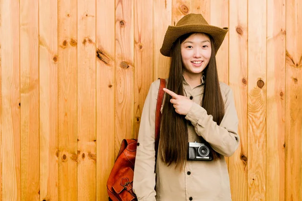 年轻的中国女旅行家一边微笑着一边指指点点 在空旷的空间里展示着一些东西 — 图库照片