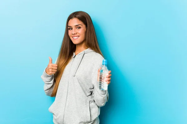 年轻健康的女人微笑着举着水瓶 举起大拇指 — 图库照片