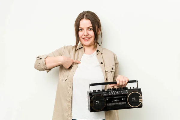 年轻的卷曲女人拿着一台复古收音机 手拉手指向一个衬衫复制空间 自豪而自信 — 图库照片