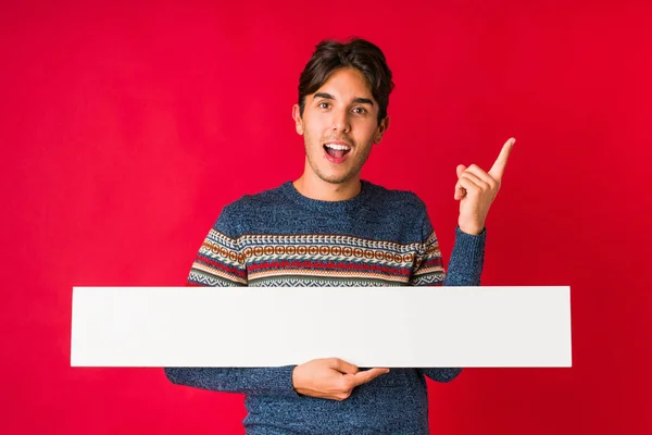 Mladý Muž Drží Plakát Vesele Ukazuje Ukazováčkem Pryč — Stock fotografie