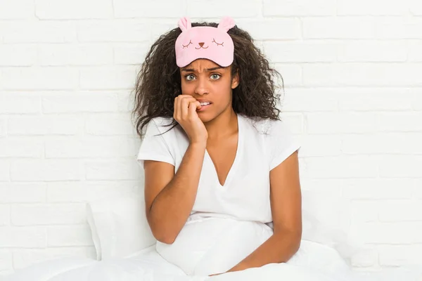 年轻的非洲裔美国女人坐在床上 戴着睡眠面具 咬着指甲 紧张而焦虑 — 图库照片