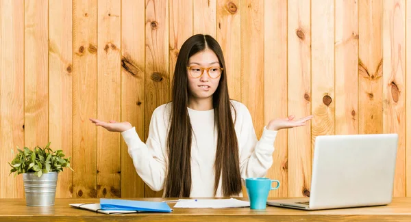 Jovem Chinesa Estudando Sua Mesa Confusa Duvidosa Ombros Encolhendo Para — Fotografia de Stock