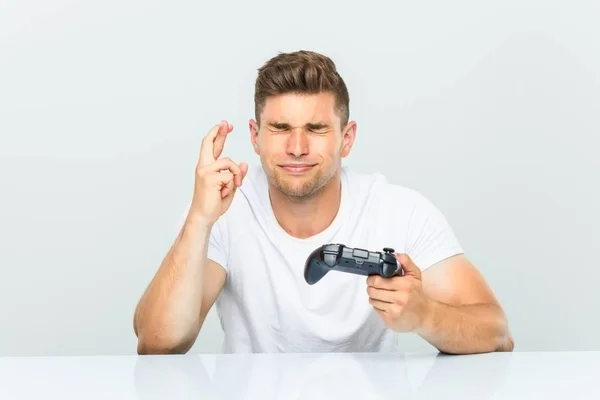 Young Man Holding Game Controller Crossing Fingers Having Luck — Stock Photo, Image