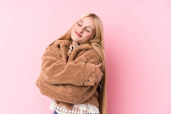 年轻的金发女郎 穿着一件外套 抱着粉红的背景 面带微笑 无忧无虑 快乐无比 — 图库照片