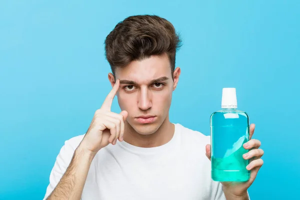 Young Caucasian Man Holding Mouthwash Pointing His Temple Finger Thinking — Stock Photo, Image