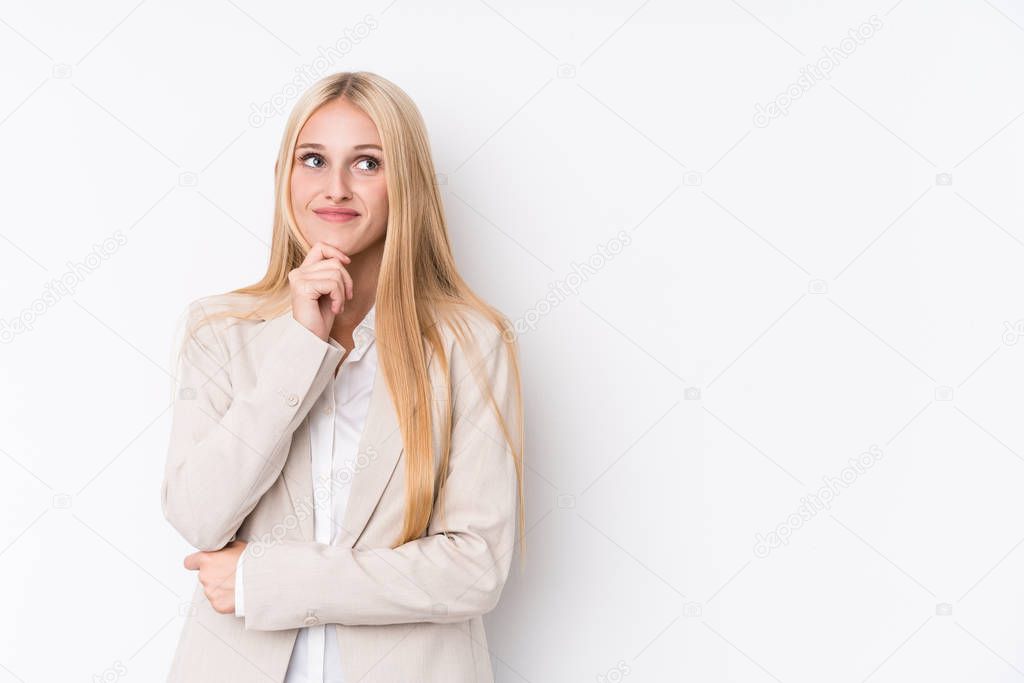 Young business blonde woman on white background looking sideways with doubtful and skeptical expression.