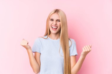 Pembe arka planda genç sarışın kadın gamsız ve heyecanlı tezahürat yapıyor. Zafer konsepti.